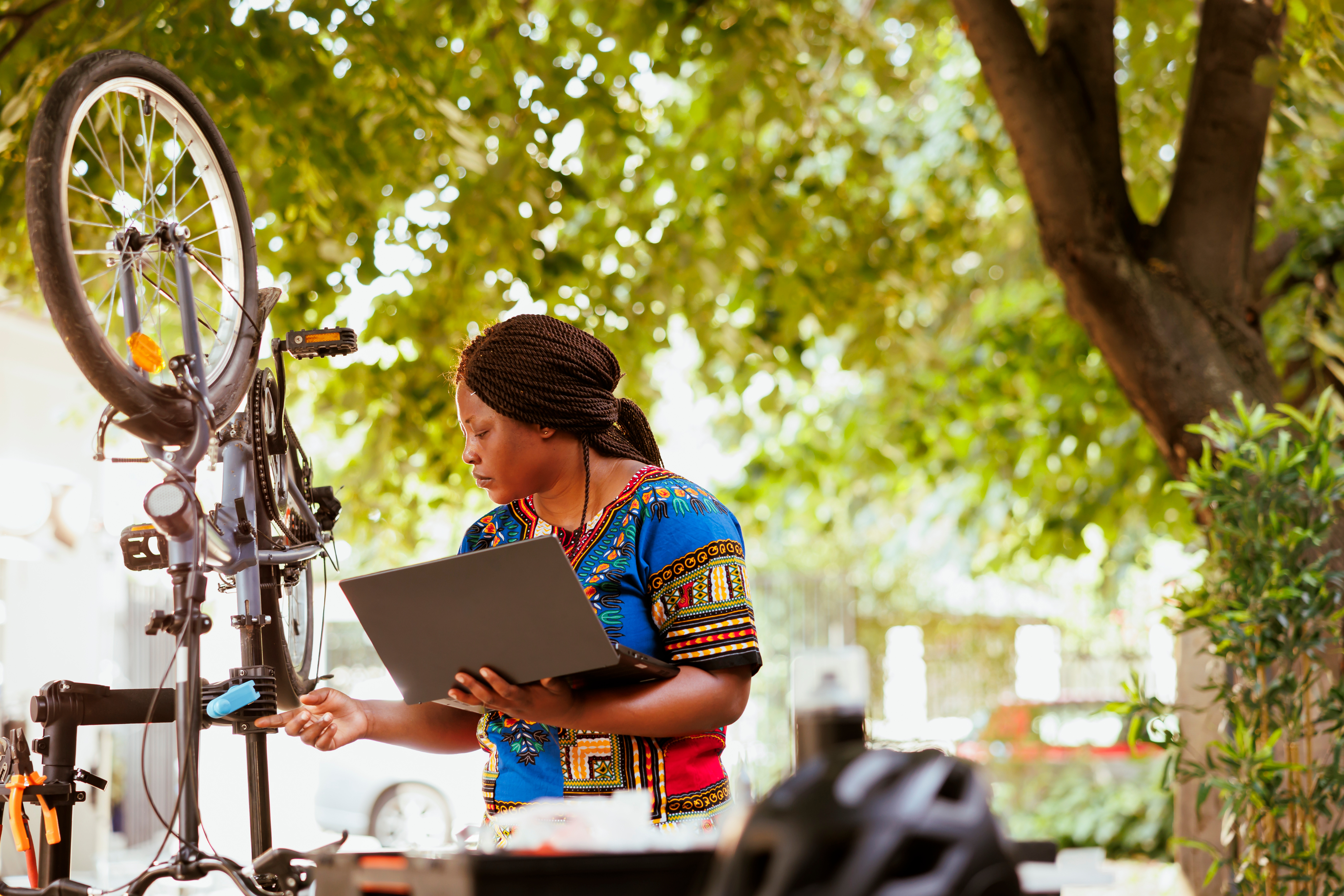 Woman with laptop and bicycle repair in community setting