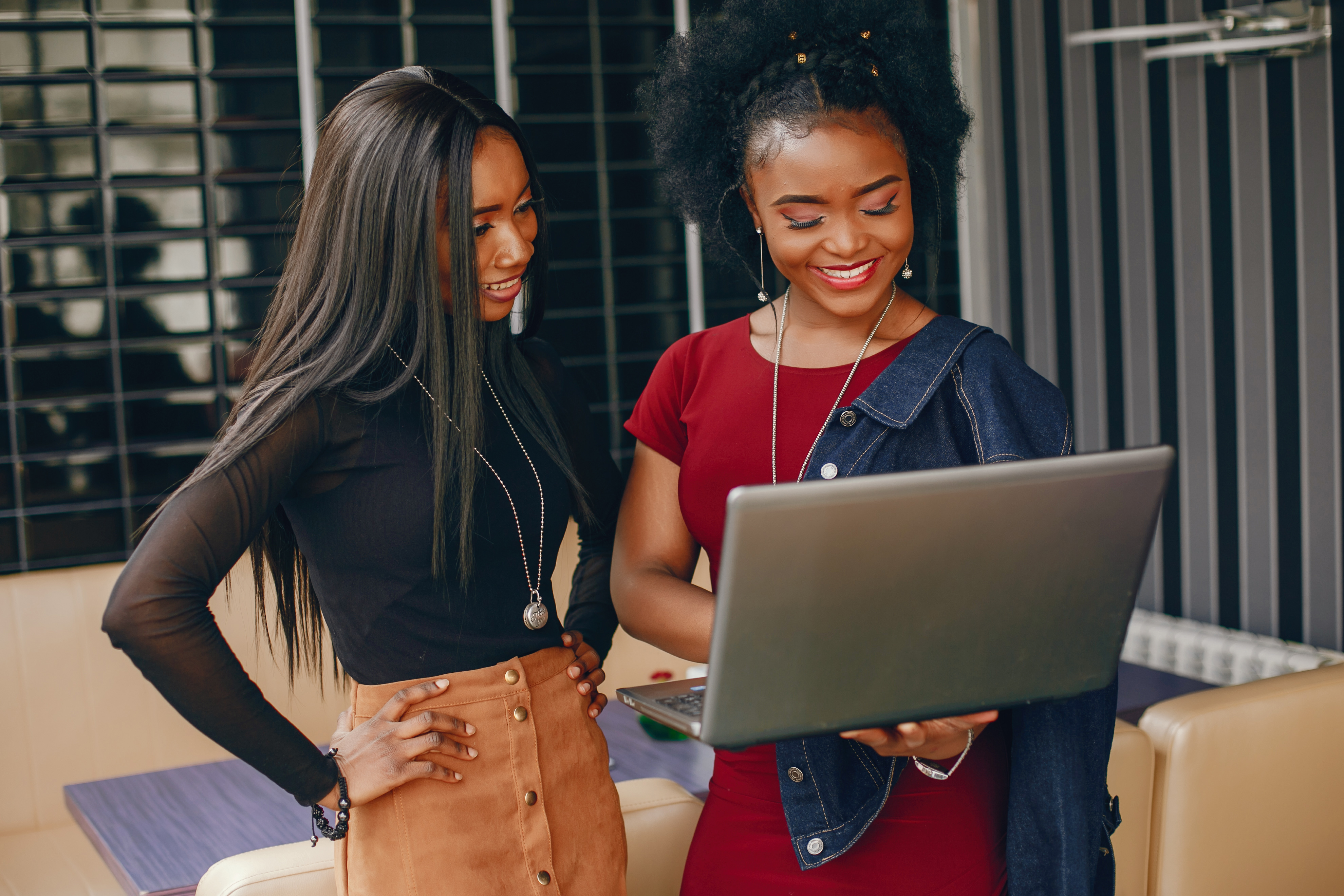 Two women standing with laptop in modern setting